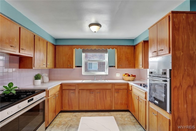 kitchen with oven, light countertops, range with gas cooktop, and a sink