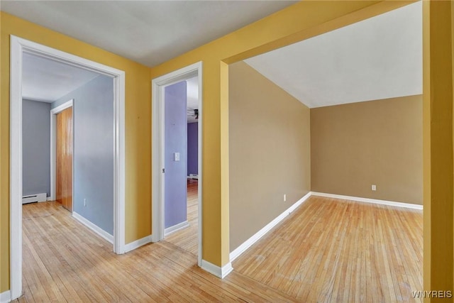 additional living space with a baseboard heating unit, baseboards, and hardwood / wood-style flooring