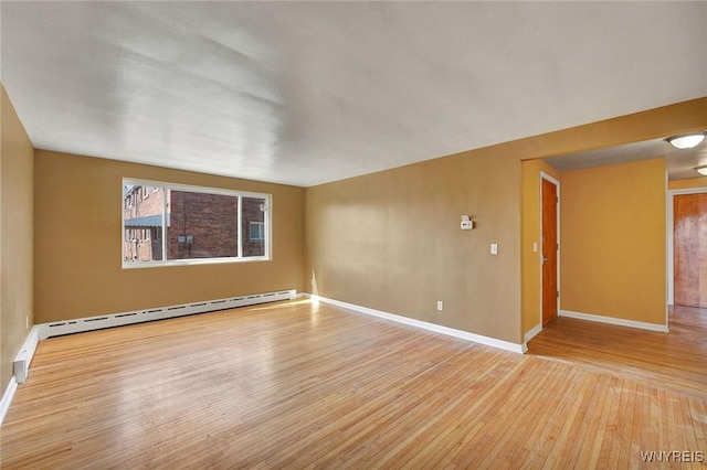 empty room featuring light wood-type flooring, a baseboard radiator, and baseboards