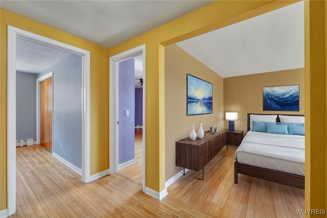 bedroom featuring a baseboard radiator, baseboards, and light wood-style flooring