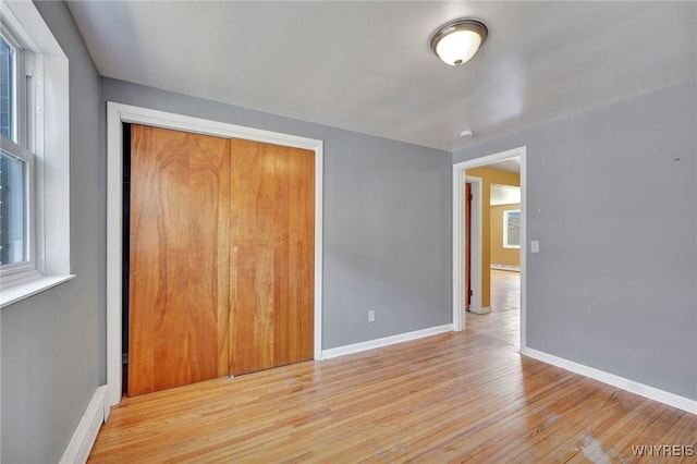 empty room with wood finished floors, baseboards, and baseboard heating