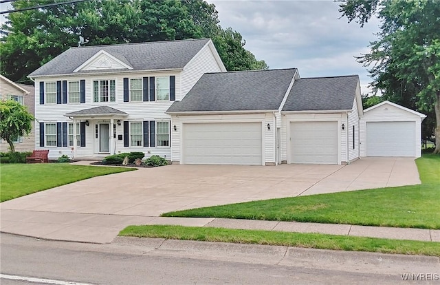 colonial-style house with an attached garage, a shingled roof, driveway, and a front yard