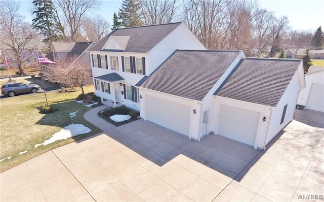 view of front of property featuring concrete driveway, a front lawn, and a garage