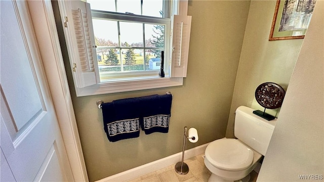 half bath featuring toilet and baseboards