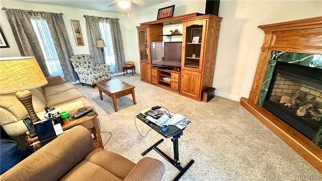 living area with a ceiling fan, light colored carpet, baseboards, and a premium fireplace