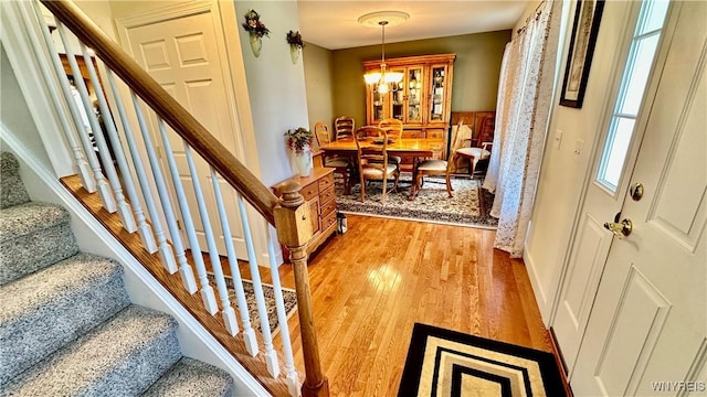 entrance foyer with an inviting chandelier, wood finished floors, and stairs