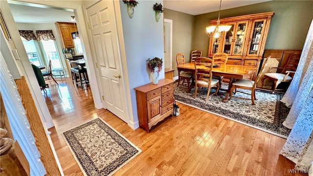 dining space with light wood-type flooring and a notable chandelier