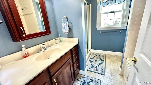 bathroom with a stall shower, vanity, and baseboards