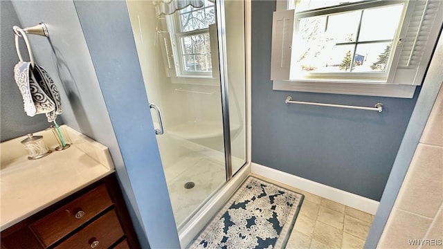 bathroom with tile patterned flooring, vanity, baseboards, and a stall shower