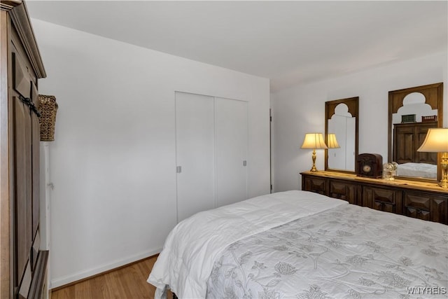 bedroom with wood finished floors, a closet, and baseboards