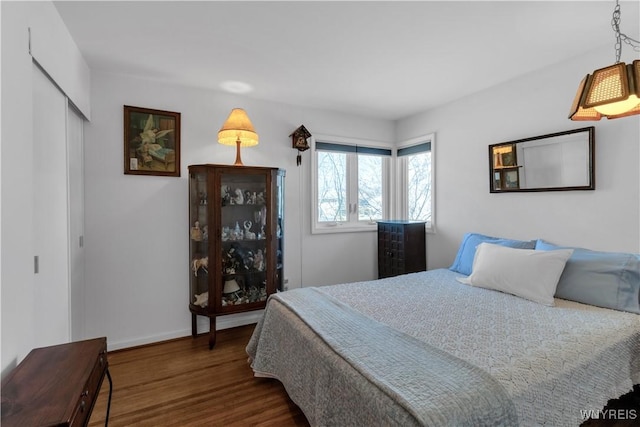 bedroom with a closet, baseboards, and wood finished floors