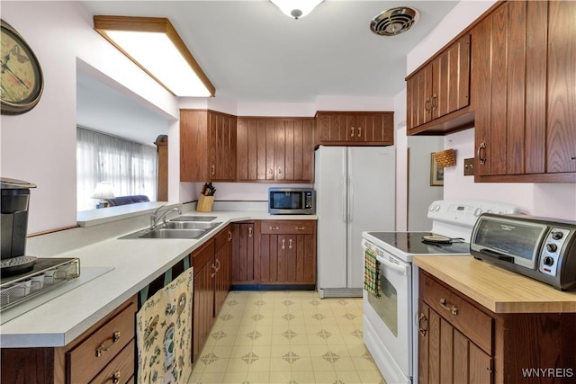 kitchen with visible vents, a toaster, light floors, white appliances, and a sink