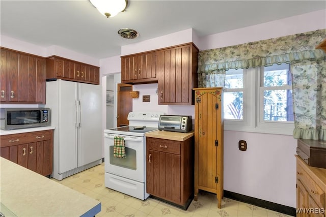 kitchen with baseboards, a toaster, light floors, light countertops, and white appliances