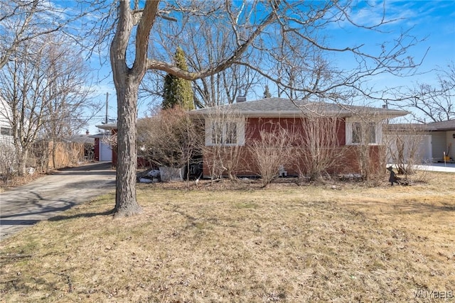 ranch-style home with brick siding, driveway, a chimney, and a front yard