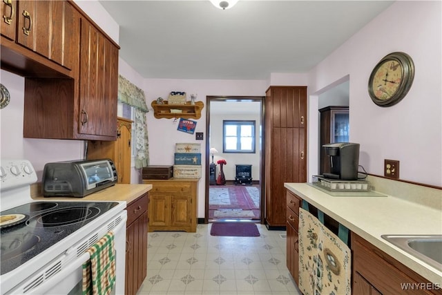 kitchen with a toaster, light countertops, electric stove, and brown cabinetry