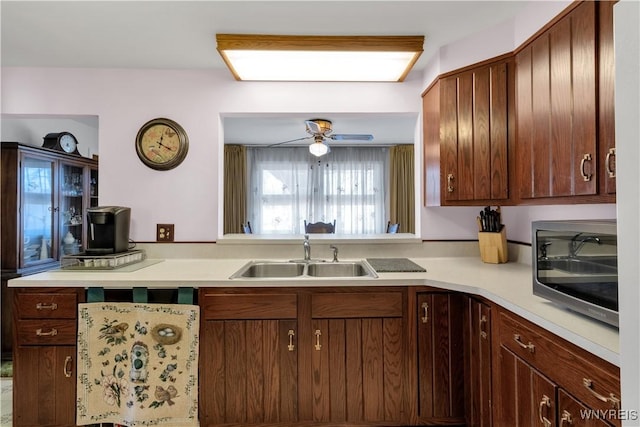 kitchen featuring stainless steel microwave, light countertops, a ceiling fan, and a sink