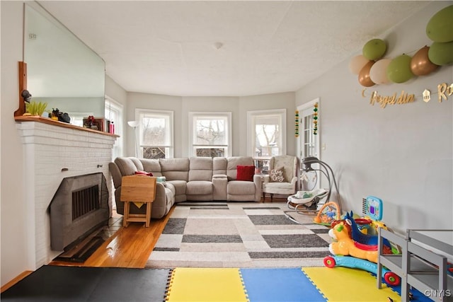 living room featuring a brick fireplace and wood finished floors