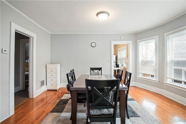 dining room featuring visible vents, ornamental molding, baseboards, and wood finished floors