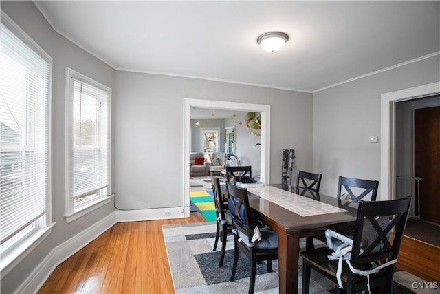 dining space with baseboards, light wood-type flooring, and ornamental molding