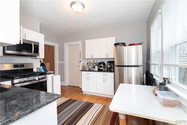 kitchen with white cabinets, light wood-type flooring, and appliances with stainless steel finishes