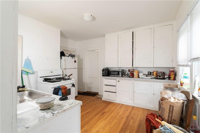 kitchen featuring light wood-type flooring, a sink, white appliances, white cabinets, and light countertops