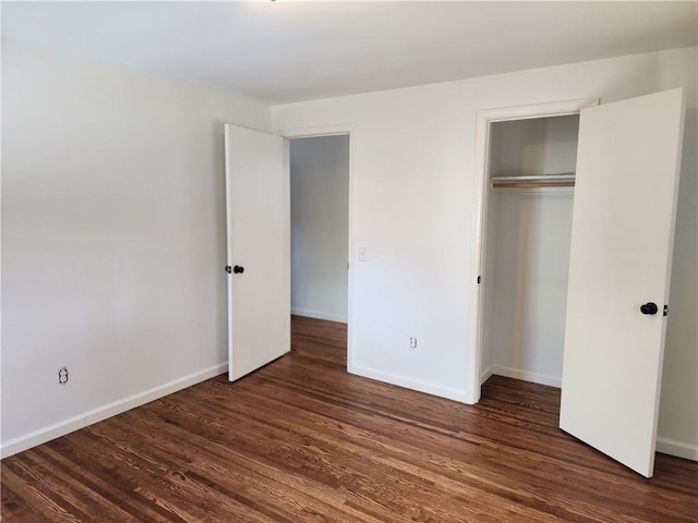 unfurnished bedroom with dark wood-type flooring, baseboards, and a closet