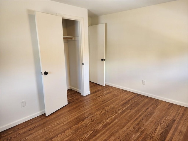 unfurnished bedroom featuring wood finished floors, baseboards, and a closet