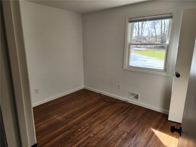 unfurnished room featuring visible vents, baseboards, and dark wood-style floors