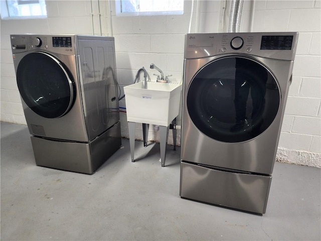 laundry room with laundry area, independent washer and dryer, and concrete block wall