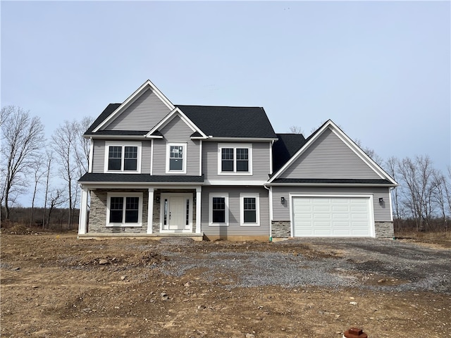 view of front facade featuring stone siding, covered porch, driveway, and a garage