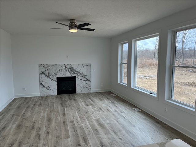 unfurnished living room featuring a healthy amount of sunlight, a fireplace, baseboards, and wood finished floors