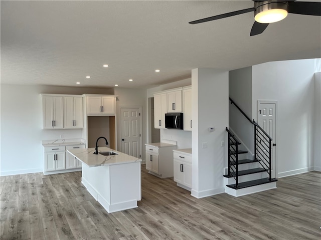 kitchen featuring light wood-style flooring, a center island with sink, and a sink