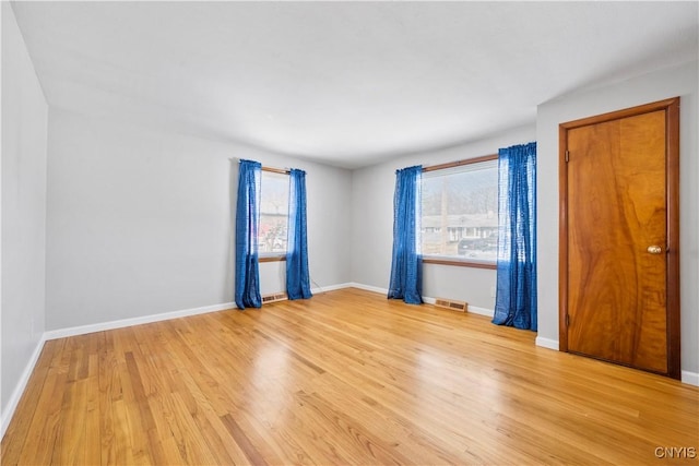 unfurnished room with light wood-style floors, visible vents, and baseboards