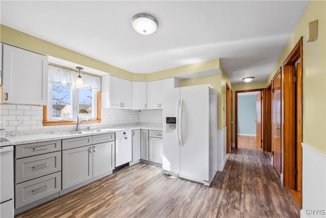 kitchen with dark wood-style floors, white appliances, gray cabinetry, and a sink