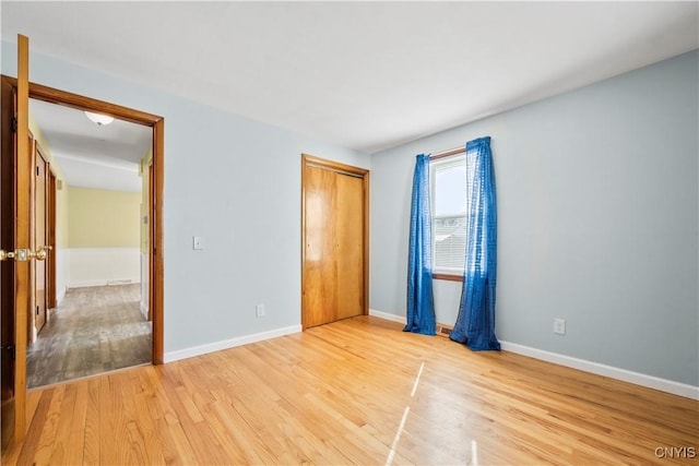 unfurnished bedroom with light wood-style floors, a closet, and baseboards