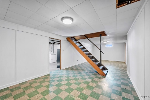 basement with tile patterned floors, stairway, washer / dryer, and baseboards