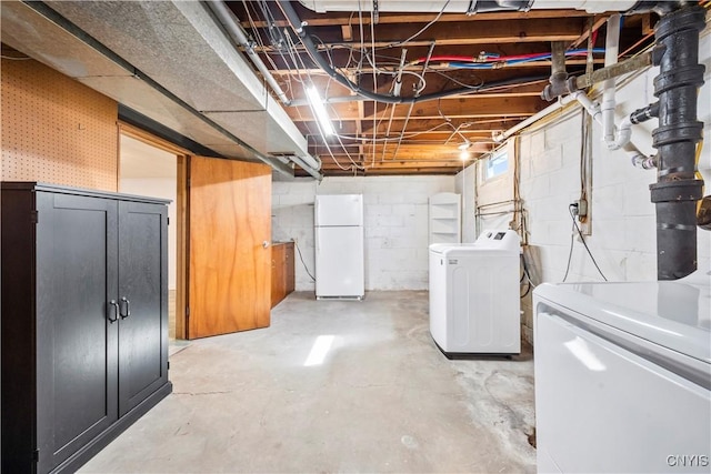 unfinished basement with separate washer and dryer and freestanding refrigerator