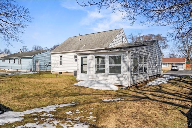 rear view of property featuring a yard and roof with shingles