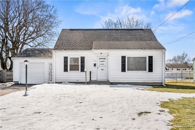 view of front facade featuring a garage, roof with shingles, and fence