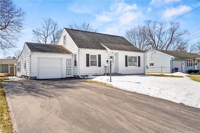 view of front of home with aphalt driveway, an attached garage, and a shingled roof