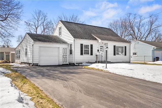 view of front facade featuring a garage, roof with shingles, and aphalt driveway