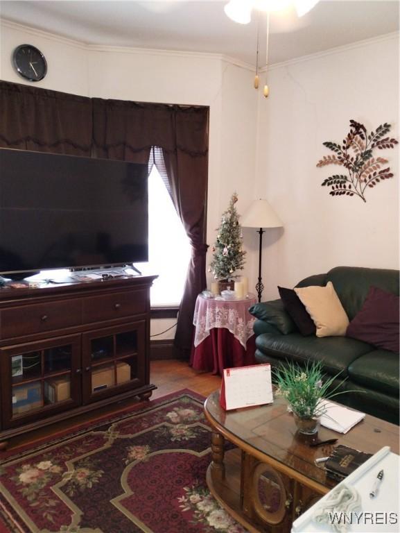 living area with wood finished floors and ornamental molding