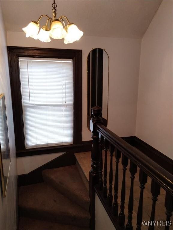 stairs featuring a chandelier