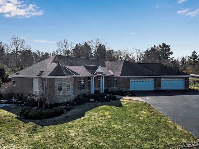 single story home with aphalt driveway, an attached garage, and a front yard