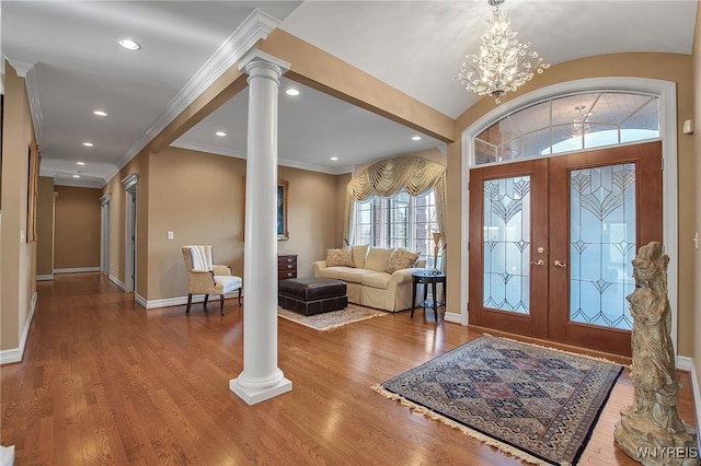 entrance foyer featuring crown molding, decorative columns, wood finished floors, and baseboards