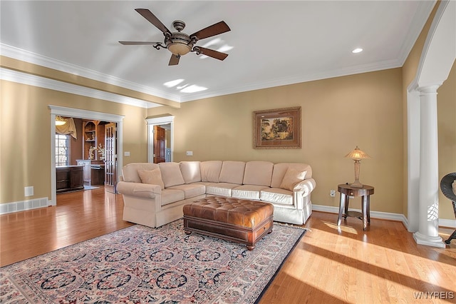 living area with visible vents, crown molding, ornate columns, and wood finished floors