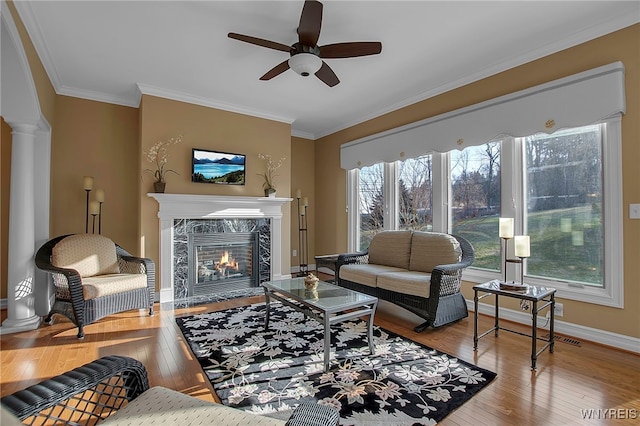 living room featuring decorative columns, hardwood / wood-style floors, a high end fireplace, and ornamental molding