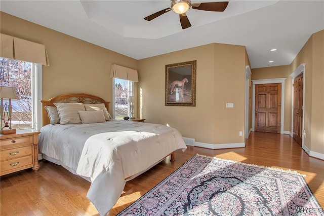 bedroom with baseboards, multiple windows, and wood finished floors