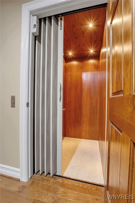 hallway featuring elevator and wood finished floors