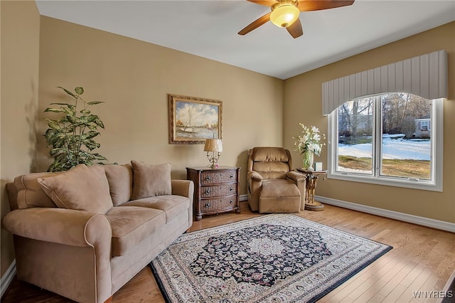 living area featuring a ceiling fan, wood finished floors, and baseboards